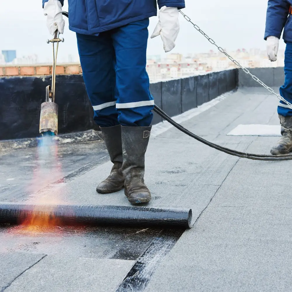 Bitumen dakbedekking wordt gebrand op een plat dak