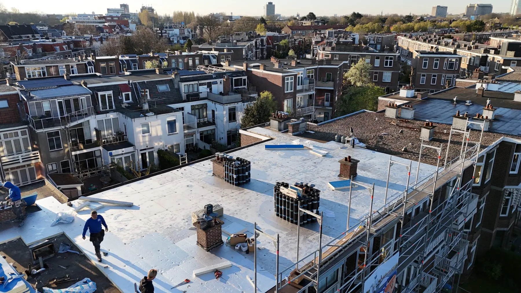 Renovatie van een groot plat dak in de stad, met dakdekkers van MACO aan het werk