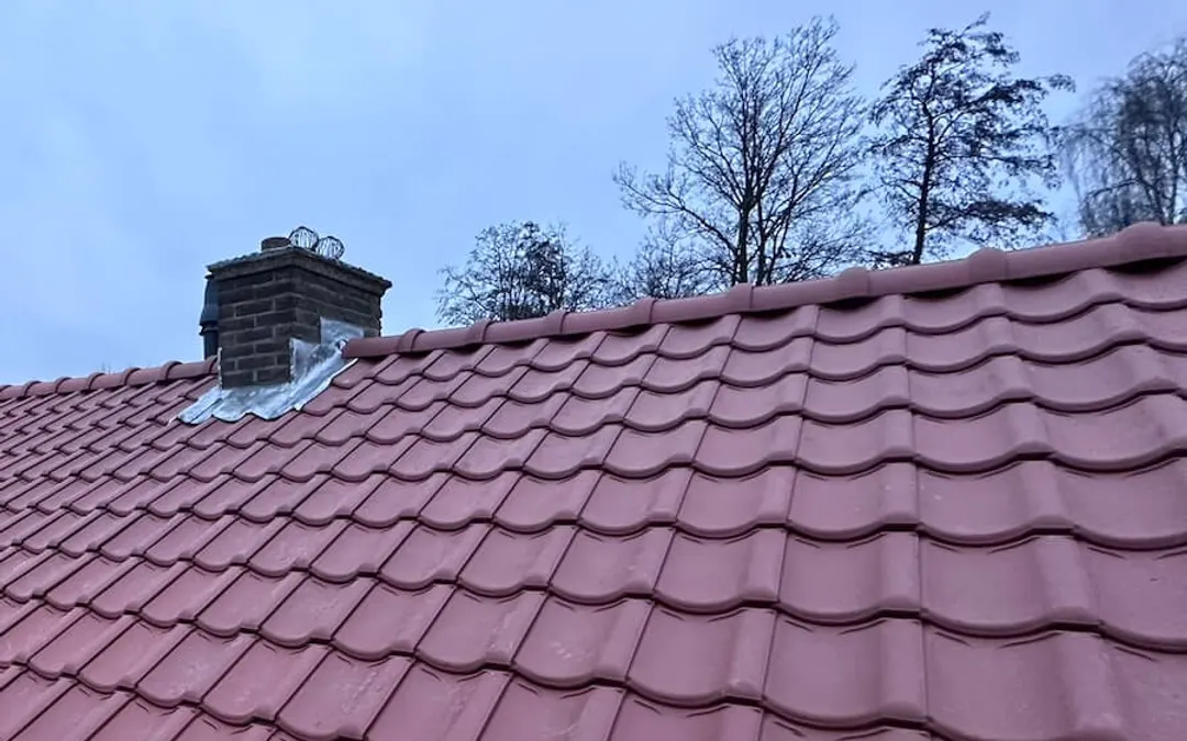 Na: pannendak met nieuwe rode keramische dakpannen en nieuw lood rond de schoorsteen